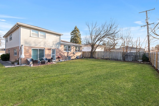 rear view of property featuring a patio, a lawn, brick siding, and a fenced backyard