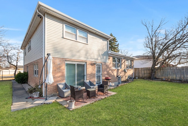 back of house with a patio, a yard, fence, and brick siding