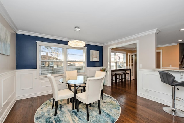 dining room featuring dark wood finished floors, wainscoting, and crown molding