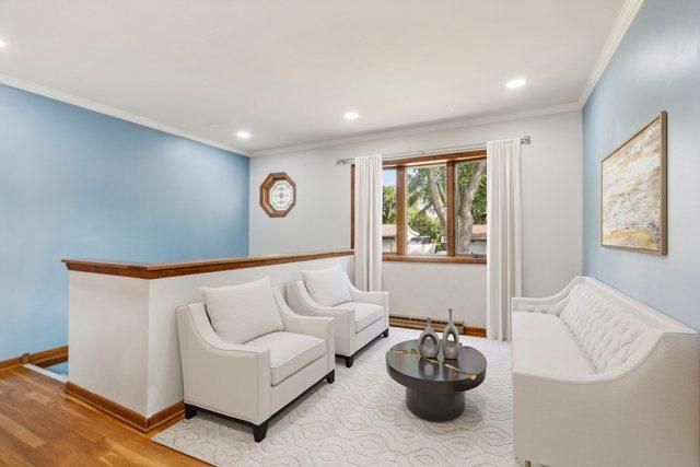 living room featuring hardwood / wood-style floors, baseboard heating, and crown molding