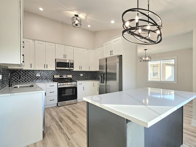 kitchen featuring white cabinets, pendant lighting, a kitchen island, and stainless steel appliances