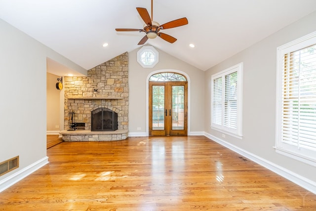 unfurnished living room with french doors, vaulted ceiling, ceiling fan, a fireplace, and light hardwood / wood-style floors