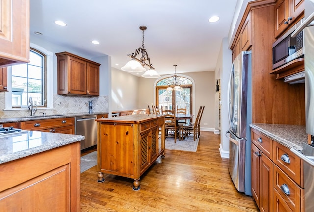 kitchen featuring pendant lighting, a center island, sink, light wood-type flooring, and stainless steel appliances