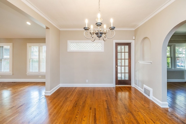 unfurnished dining area with hardwood / wood-style flooring, a notable chandelier, and ornamental molding