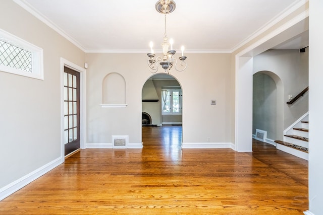 unfurnished dining area featuring a notable chandelier, wood-type flooring, and crown molding