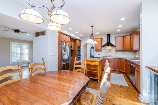 dining space featuring ceiling fan with notable chandelier, light wood-type flooring, sink, and beverage cooler