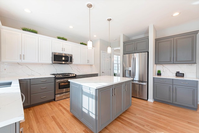 kitchen with white cabinetry, gray cabinets, appliances with stainless steel finishes, decorative light fixtures, and a center island