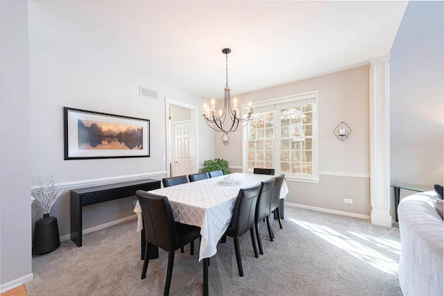 dining area with light colored carpet, ornate columns, and an inviting chandelier