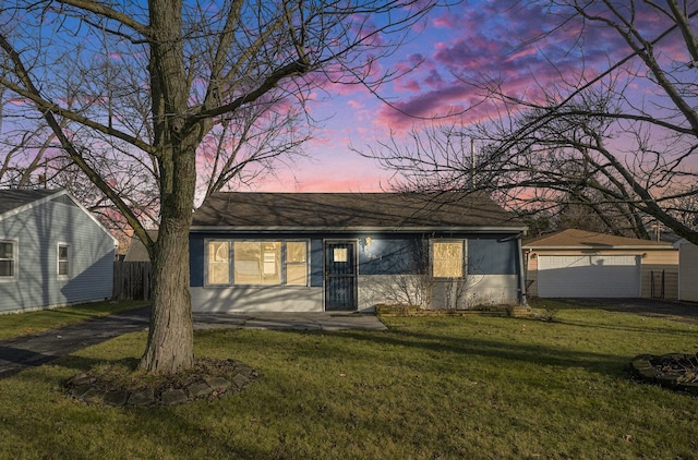 ranch-style home with a garage, an outdoor structure, and a lawn