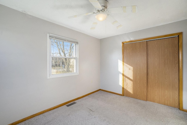 unfurnished bedroom featuring light carpet, a closet, and ceiling fan