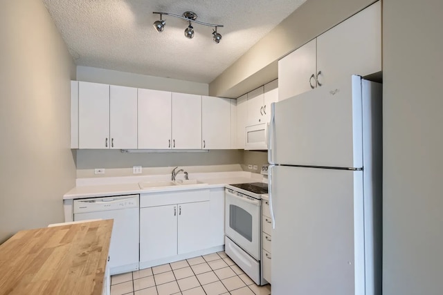 kitchen with sink, white appliances, white cabinetry, a textured ceiling, and light tile patterned flooring