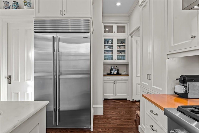 kitchen featuring built in refrigerator, dark hardwood / wood-style floors, stove, and white cabinets