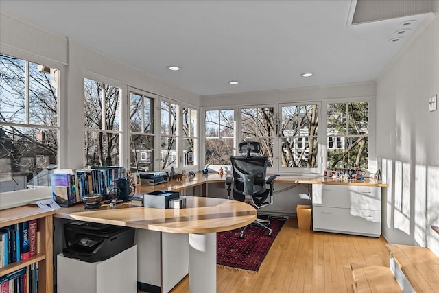 home office with ornamental molding, built in desk, and light wood-type flooring