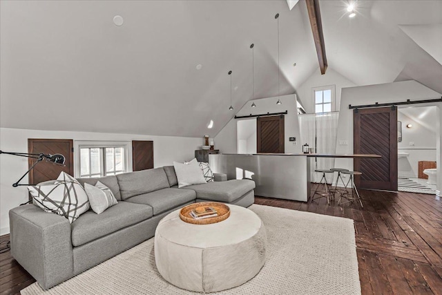 living room with dark wood-type flooring, lofted ceiling with beams, and a barn door