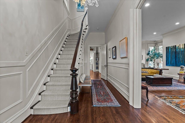 foyer featuring crown molding, an inviting chandelier, and dark hardwood / wood-style flooring