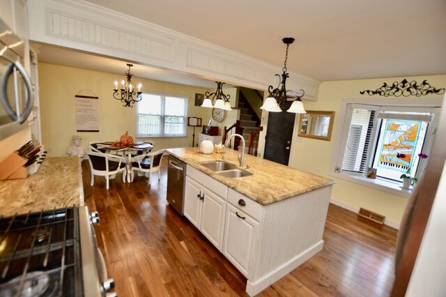 kitchen featuring gas range oven, sink, pendant lighting, dishwasher, and white cabinetry