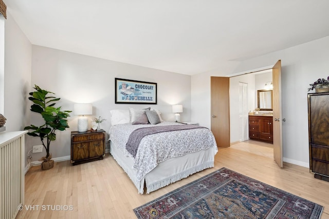 bedroom featuring connected bathroom and light hardwood / wood-style flooring