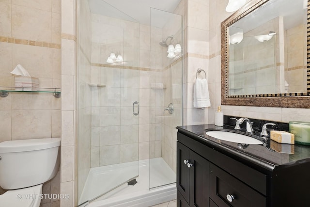 bathroom featuring vanity, a shower with door, toilet, and tile walls