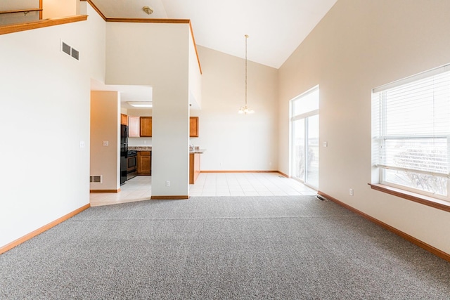 unfurnished living room with high vaulted ceiling, light colored carpet, and an inviting chandelier