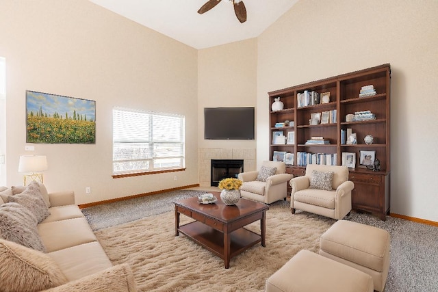 living room featuring a tile fireplace, light carpet, a towering ceiling, and ceiling fan