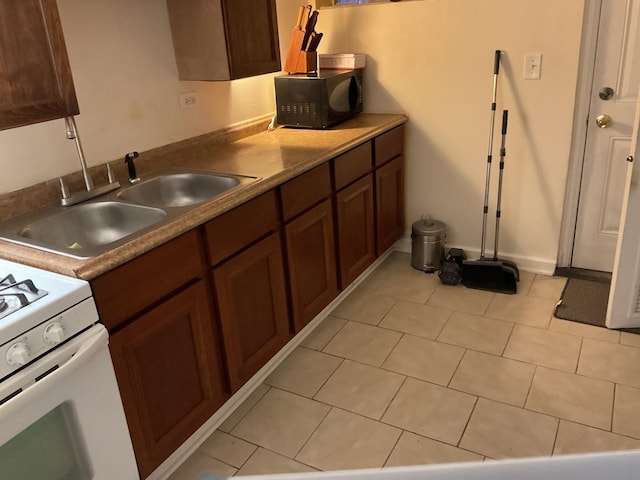 kitchen with light tile patterned flooring, white range, and sink