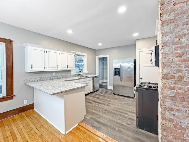 kitchen with white cabinetry, sink, light hardwood / wood-style floors, and appliances with stainless steel finishes