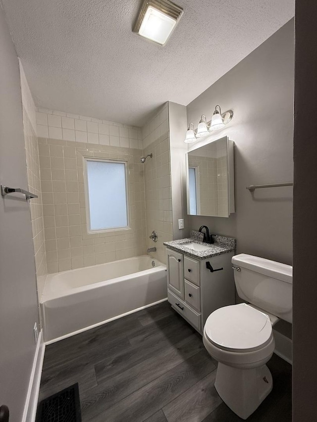 full bathroom with vanity, a textured ceiling, tiled shower / bath combo, wood-type flooring, and toilet