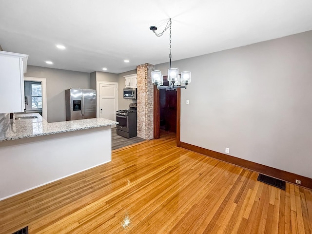 kitchen with sink, light wood-type flooring, white cabinetry, kitchen peninsula, and stainless steel appliances