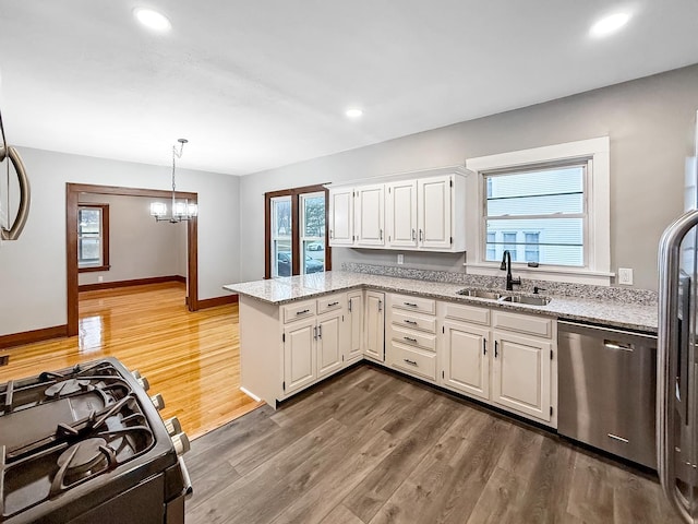 kitchen with kitchen peninsula, gas stove, sink, dishwasher, and white cabinetry