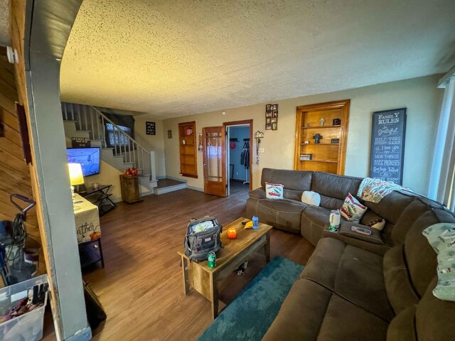 living room featuring built in shelves, hardwood / wood-style floors, and a textured ceiling