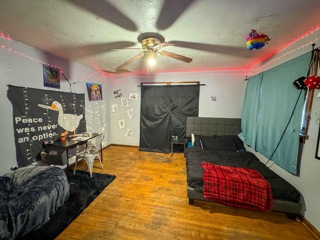 bedroom with ceiling fan, hardwood / wood-style floors, and a textured ceiling