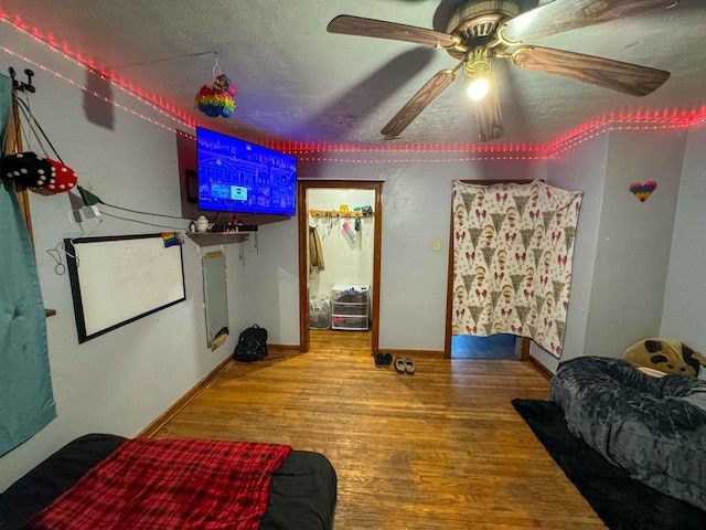 bedroom with ceiling fan, wood-type flooring, and a textured ceiling