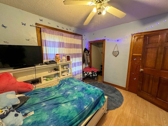 bedroom with ceiling fan, light hardwood / wood-style flooring, and a textured ceiling