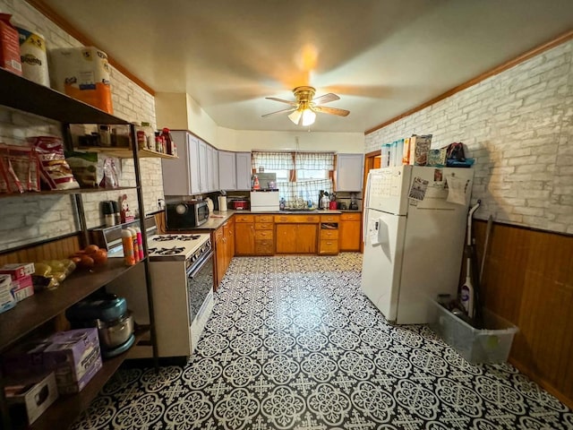 kitchen with wooden walls, ceiling fan, brick wall, and white appliances