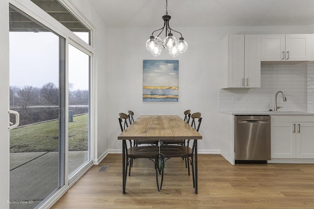 dining space featuring sink, a chandelier, and light hardwood / wood-style flooring