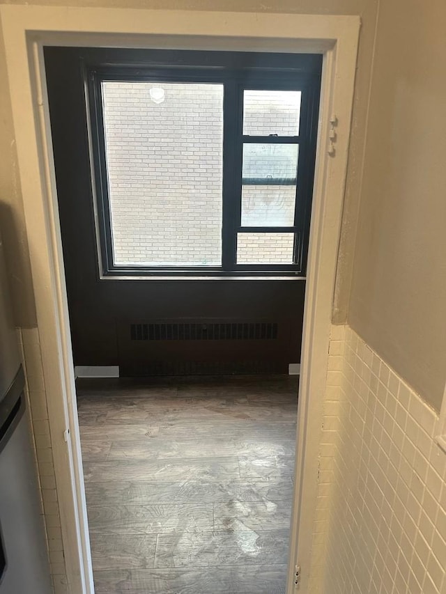 unfurnished room featuring wood-type flooring, tile walls, and radiator heating unit