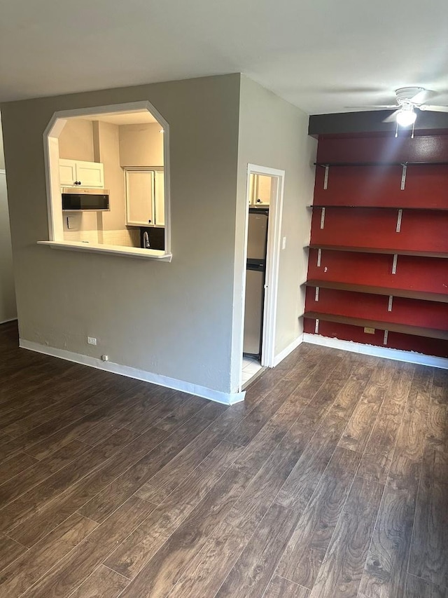 unfurnished living room featuring ceiling fan and dark wood-type flooring