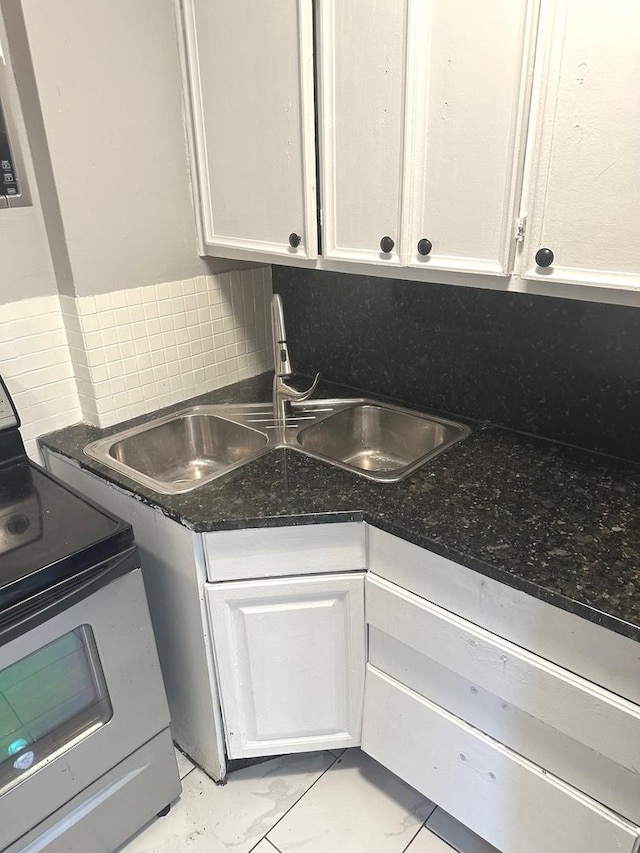 kitchen featuring electric stove, white cabinetry, backsplash, and sink