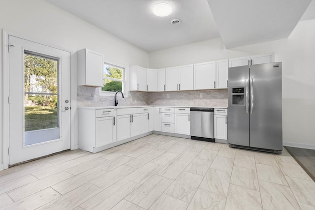 kitchen featuring backsplash, white cabinetry, sink, and stainless steel appliances