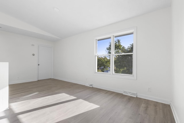 unfurnished room featuring light hardwood / wood-style floors and lofted ceiling