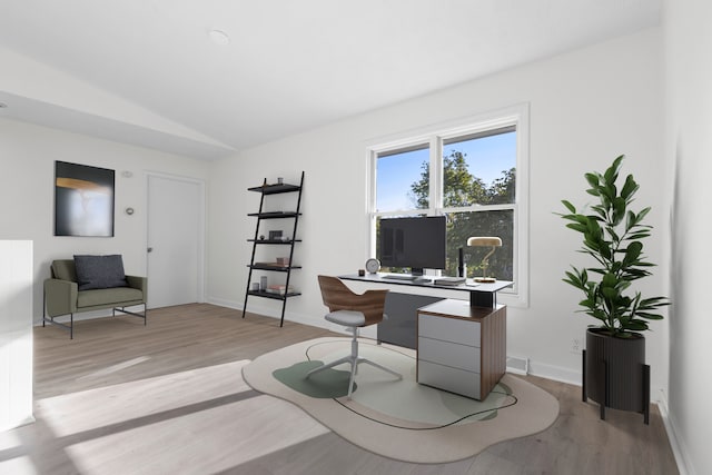 home office featuring vaulted ceiling and light hardwood / wood-style flooring