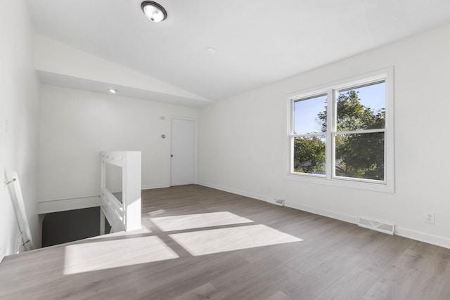 empty room with light wood-type flooring and lofted ceiling