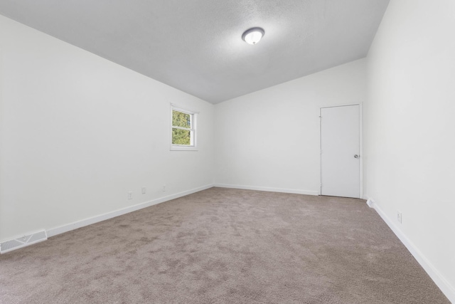 carpeted empty room with a textured ceiling and vaulted ceiling