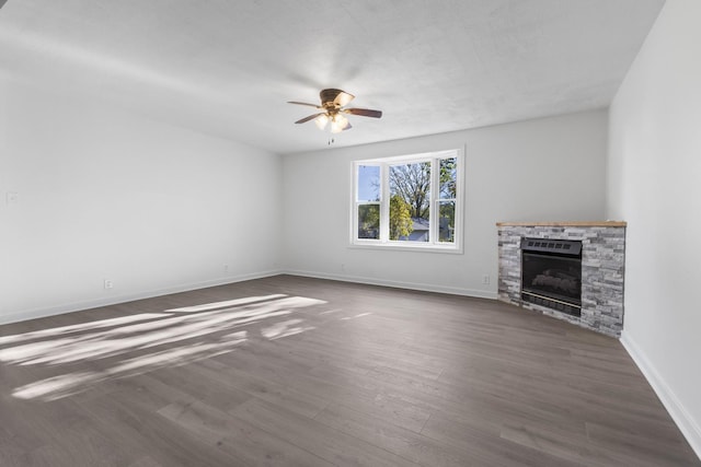 unfurnished living room featuring ceiling fan, a fireplace, and dark hardwood / wood-style floors