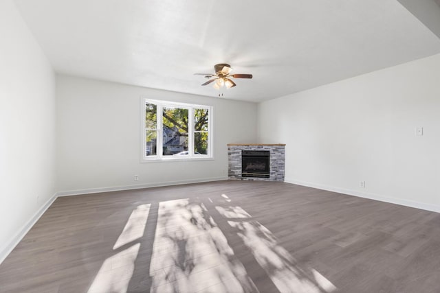 unfurnished living room featuring dark hardwood / wood-style floors, ceiling fan, and a fireplace