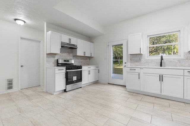 kitchen featuring backsplash, white cabinets, stainless steel stove, and a healthy amount of sunlight