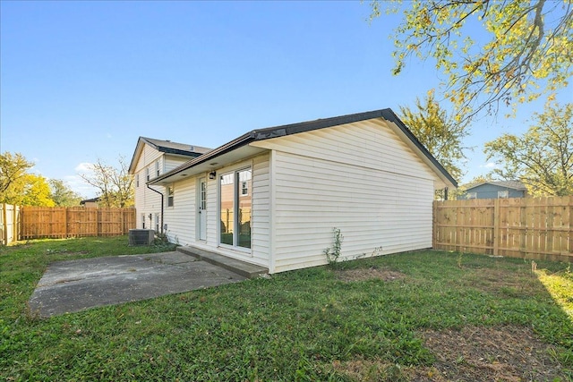 view of side of property with a lawn, a patio, and central AC