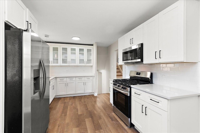 kitchen with white cabinets, dark hardwood / wood-style floors, stainless steel appliances, and tasteful backsplash