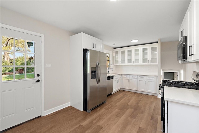 kitchen with white cabinetry, sink, decorative backsplash, appliances with stainless steel finishes, and light wood-type flooring