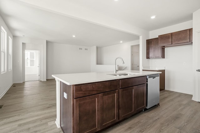 kitchen featuring dishwasher, sink, a kitchen island with sink, dark brown cabinets, and light hardwood / wood-style flooring